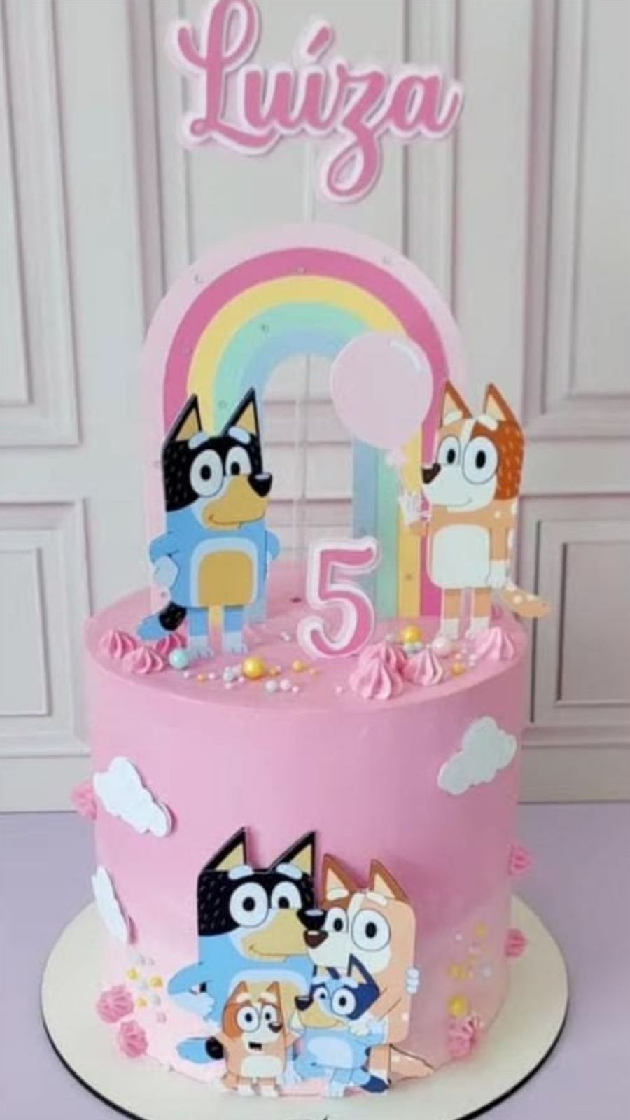 Bolo rosa com arco-íris e personagens